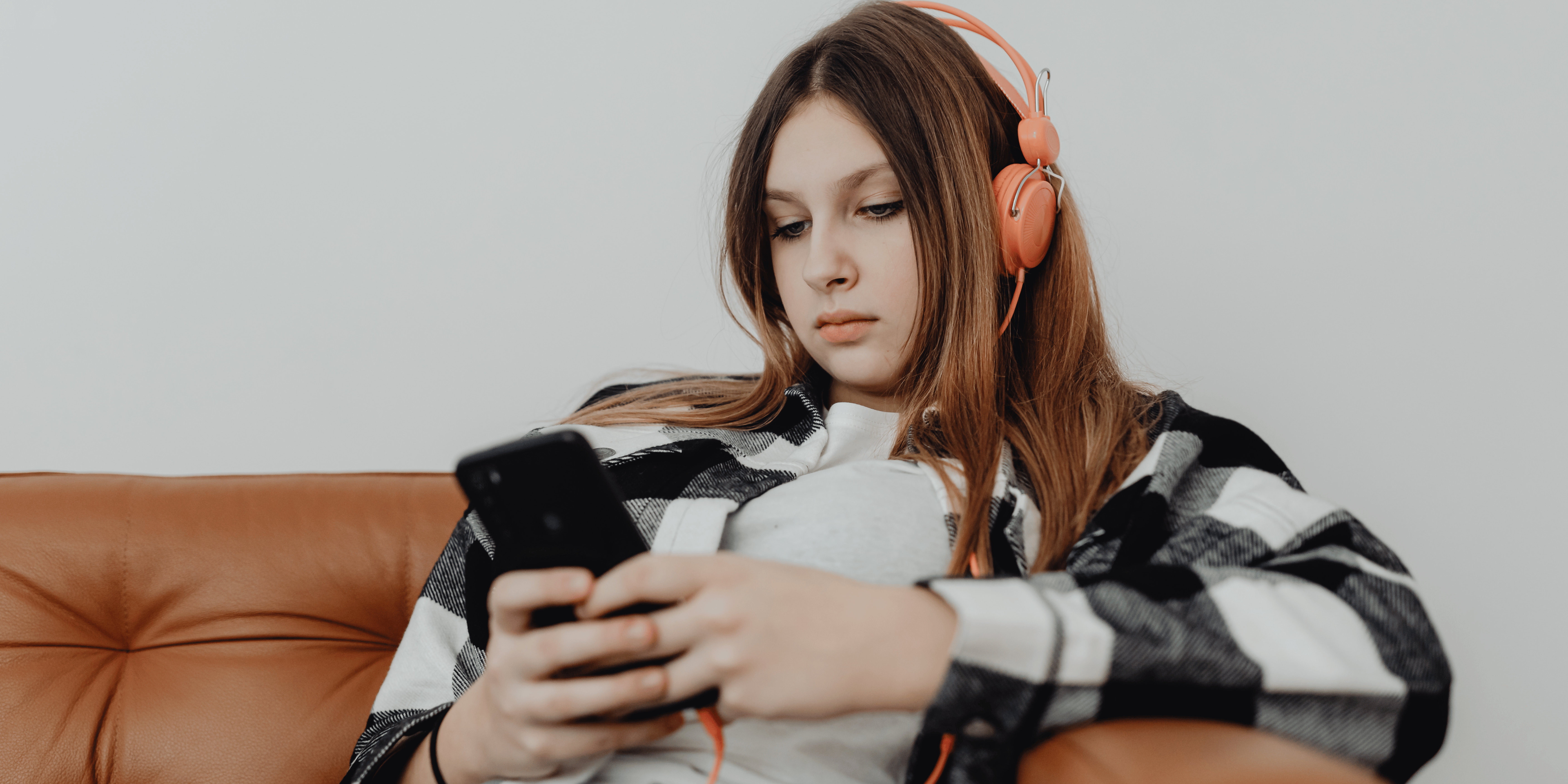 sad teenage girl wearing headphones looking at her phone