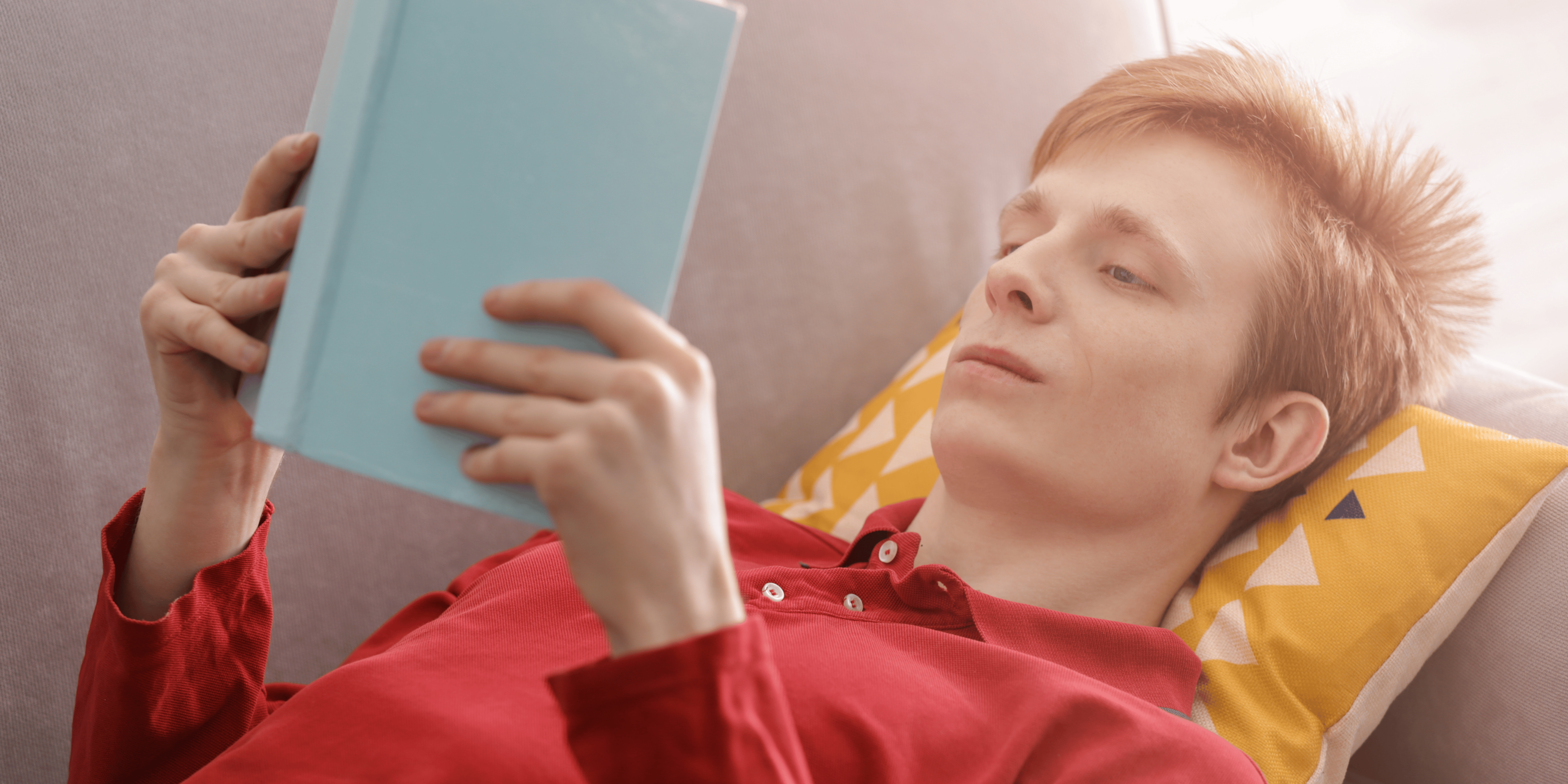 teenager lying down, reading a book